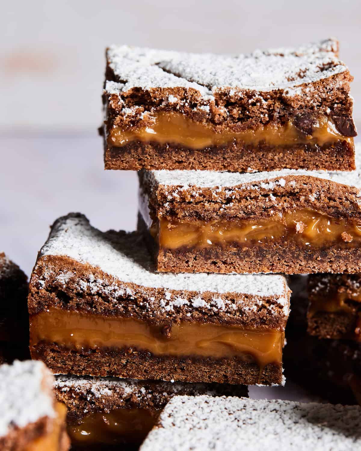 A pile of caramel brownies covered in powdered sugar.  