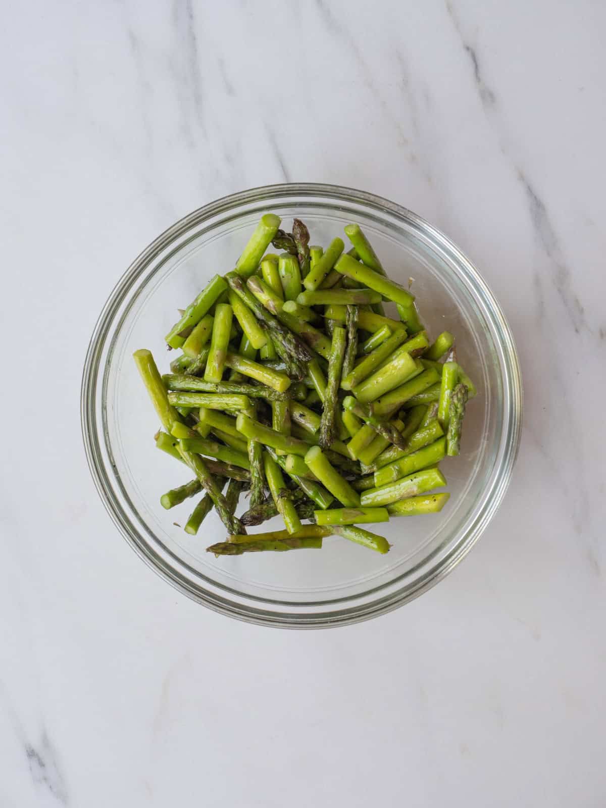 A bowl with grilled asparagus cut into about one inch pieces.