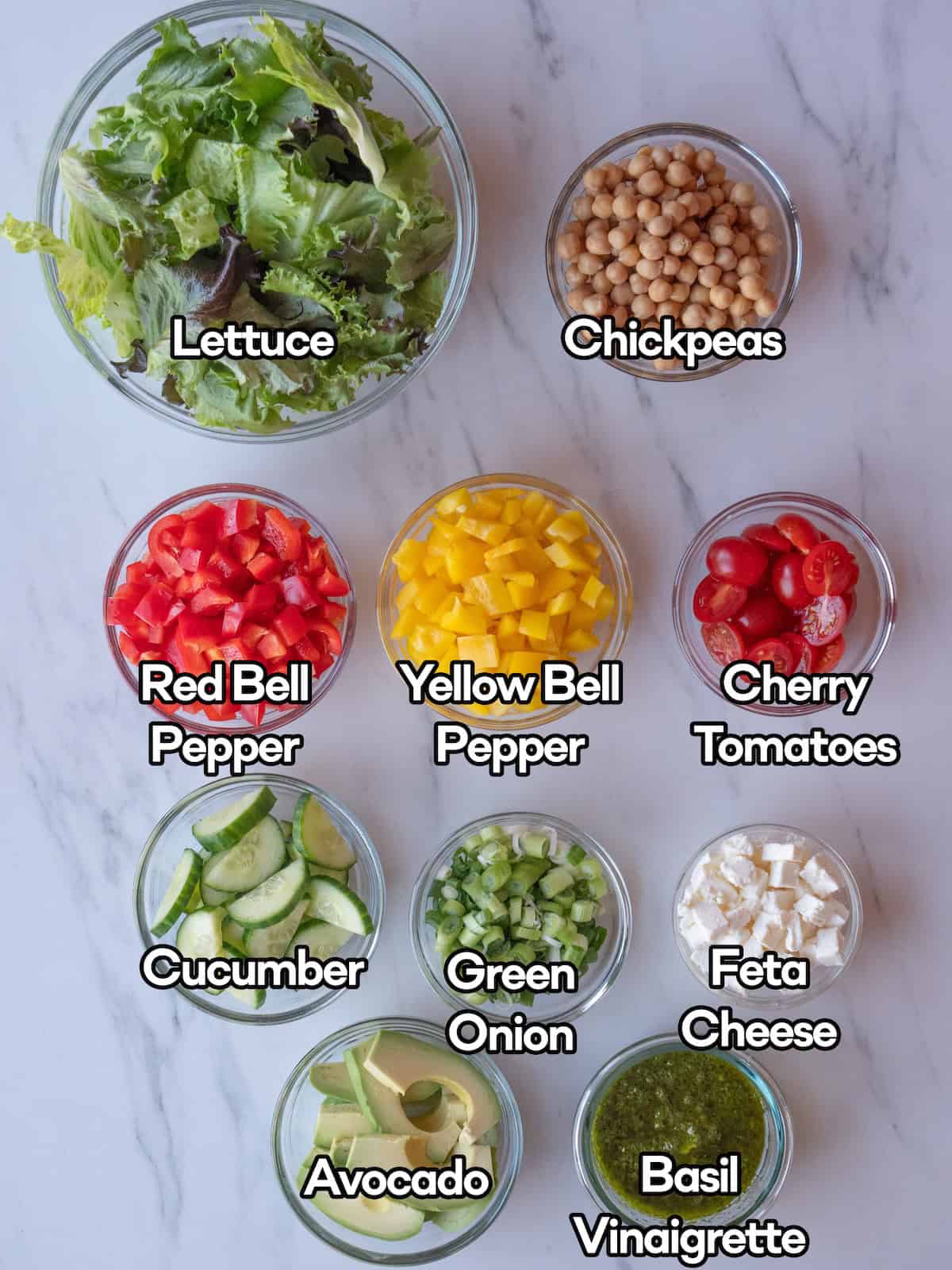 Mise en place of all ingredients to make loaded power salad along with a bowl of basil vinaigrette.