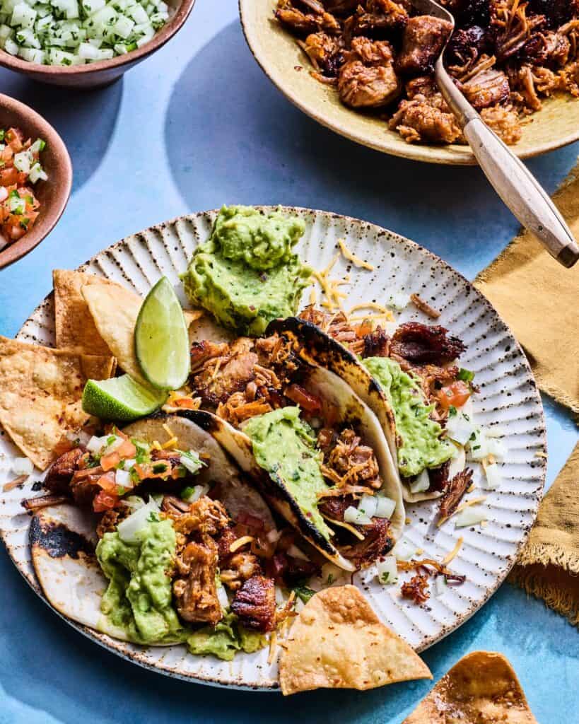 Slow Roasted Pork Carnitas in tacos with guacamole and limes