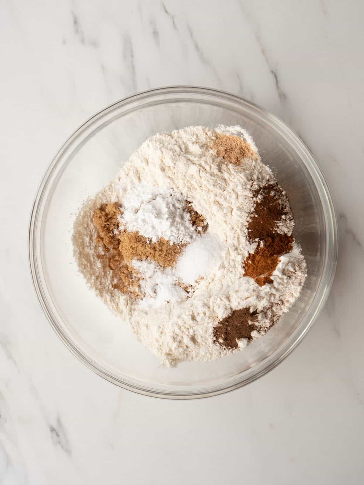 A glass mixing bowl with all dry ingredients to make donut batter.