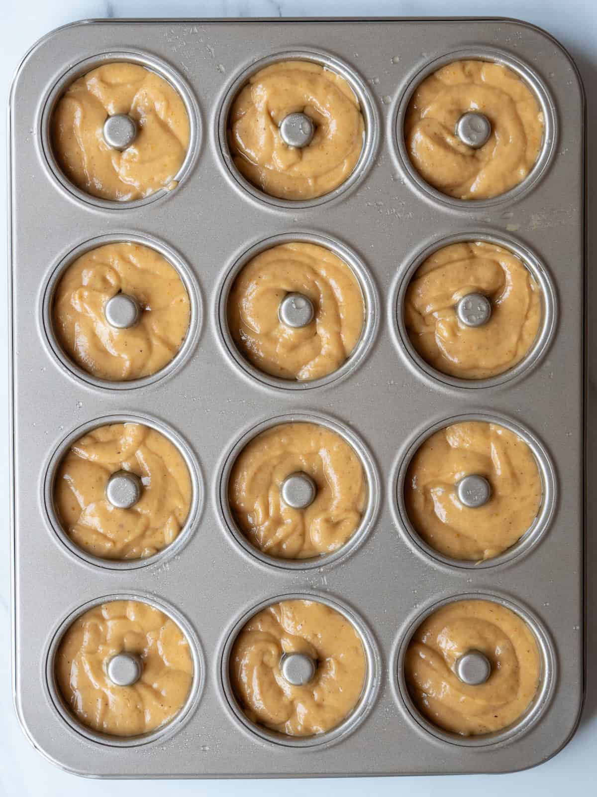 A mini donut pan with the donut batter poured into it.