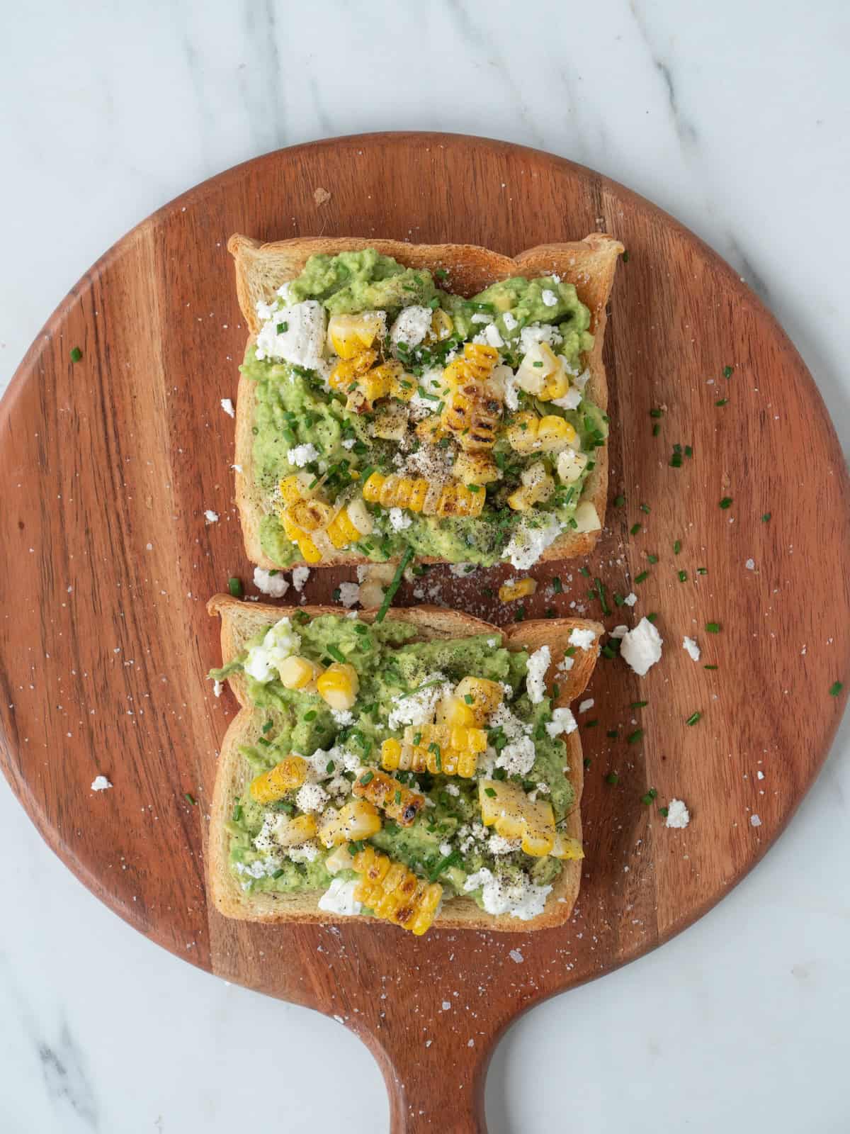 An avocado toast with crumbled goat cheese, charred corn and chives.