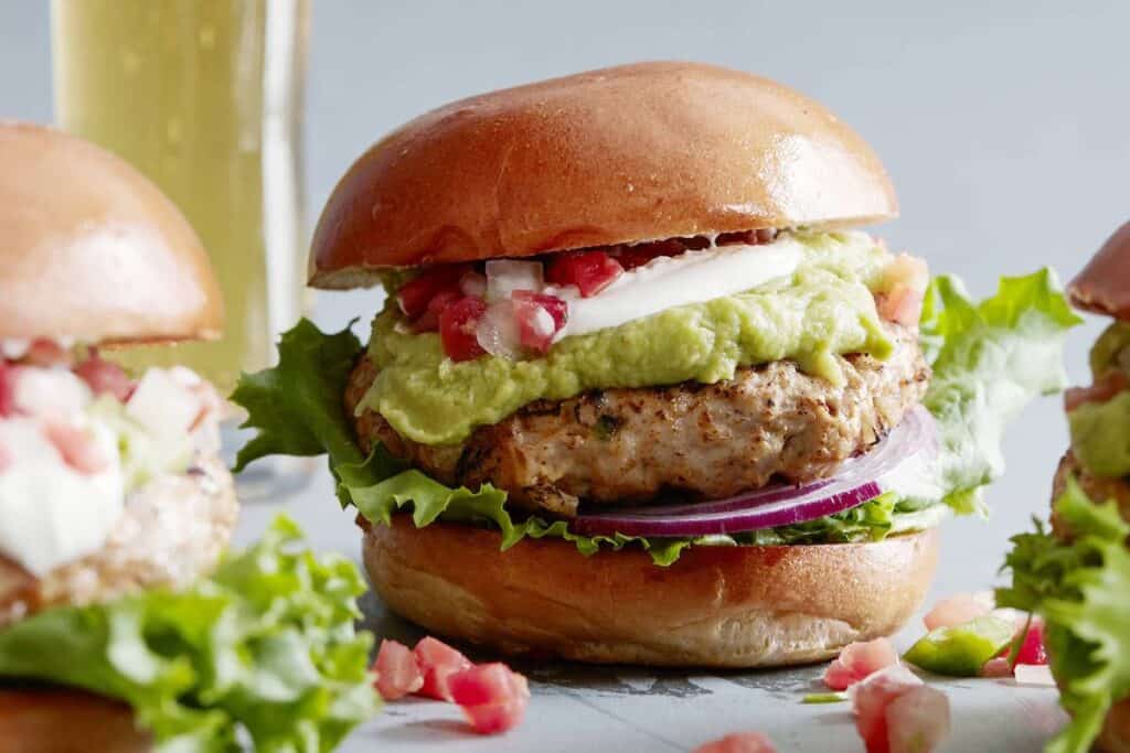 Cheddar Jalapeno Chicken burgers with guacamole, sour cream, pico, sliced red onion, and lettuce