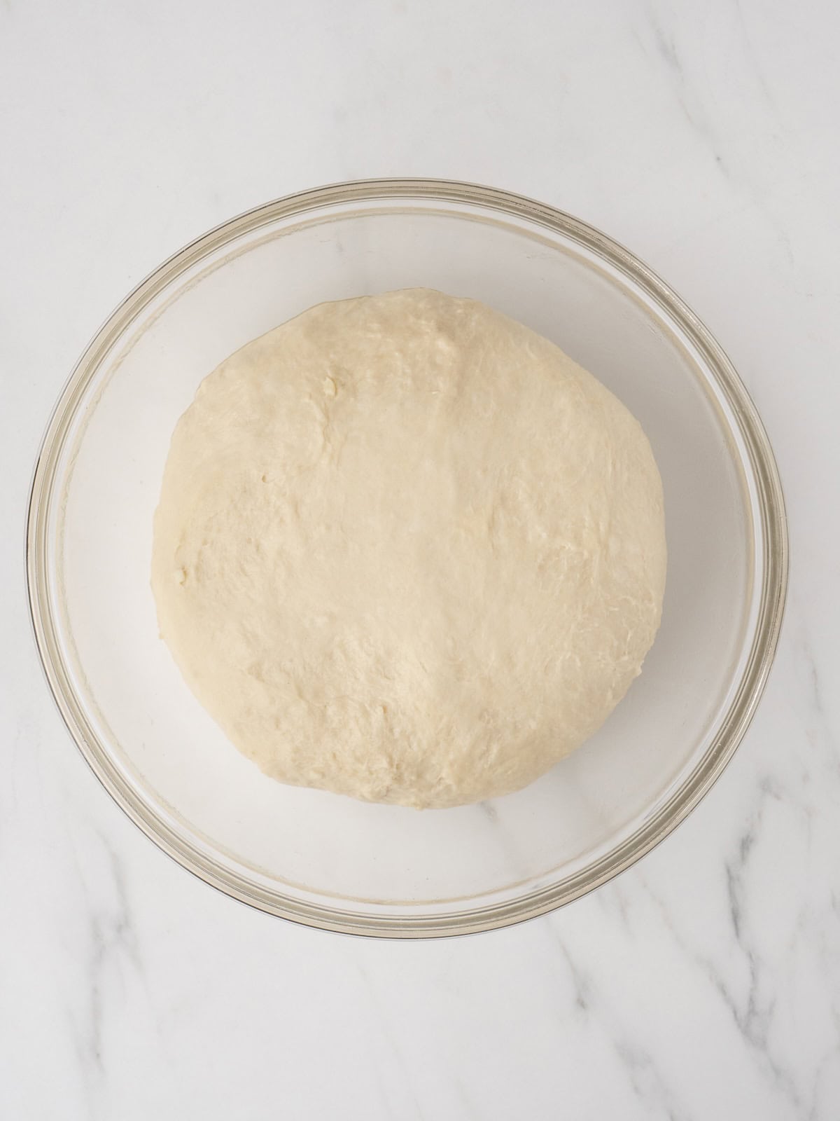 Round dough ball in glass bowl
