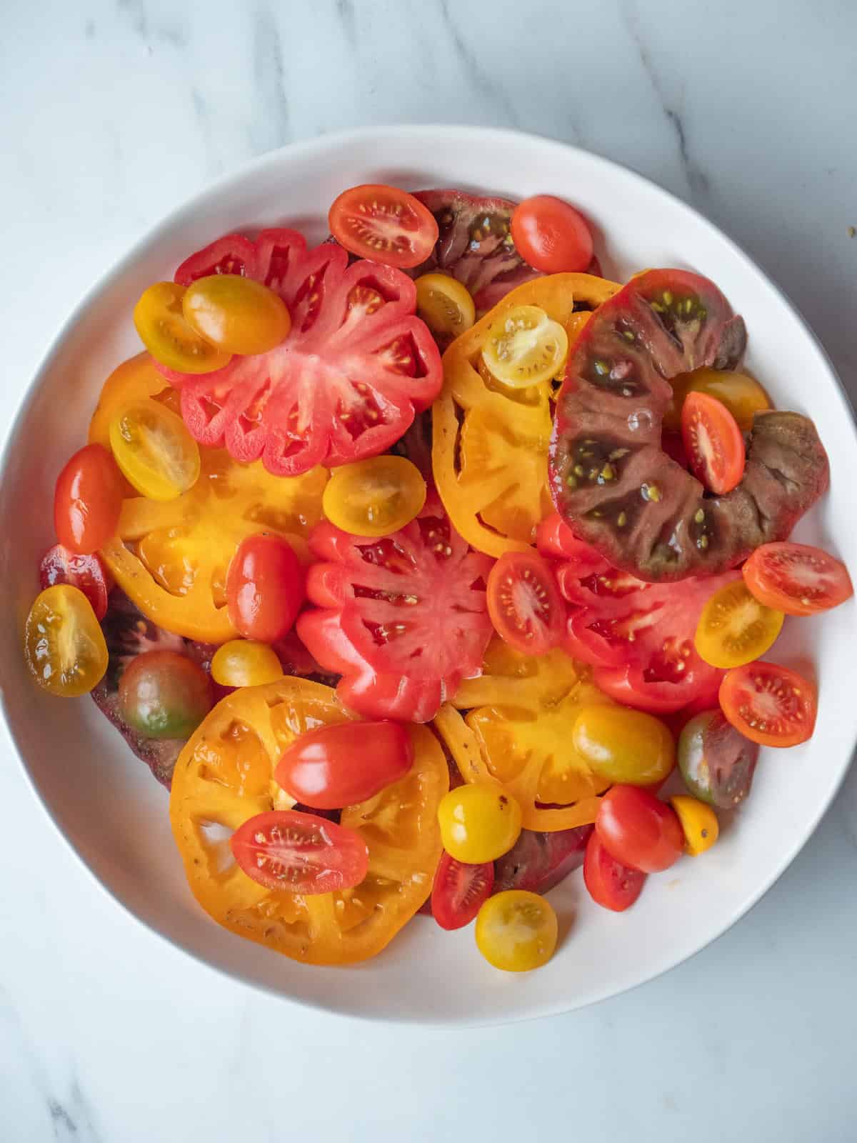 A low bowl with sliced cherry tomatoes and heirloom tomatoes.