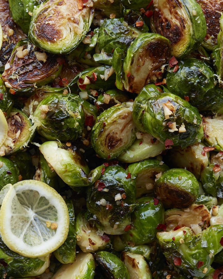 Close-up shot of brussels sprouts garnished with red pepper flakes and thin slices of lemon