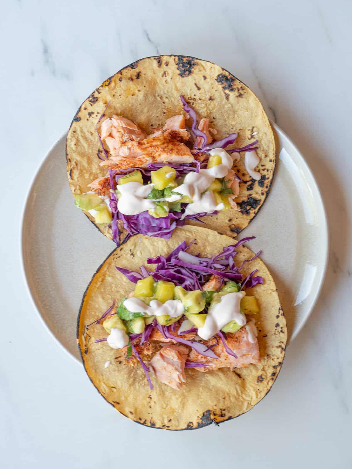 Chipotle Salmon Tacos with cabbage, avocado mango salsa, and crema