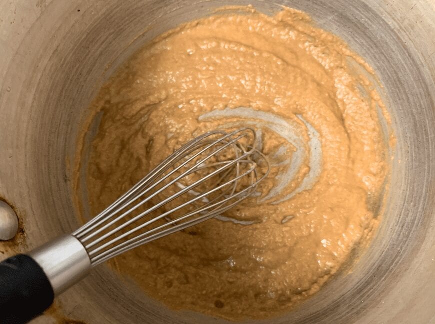 A pan with turkey drippings turned into a roux with butter and flour and a whisk in the pan.