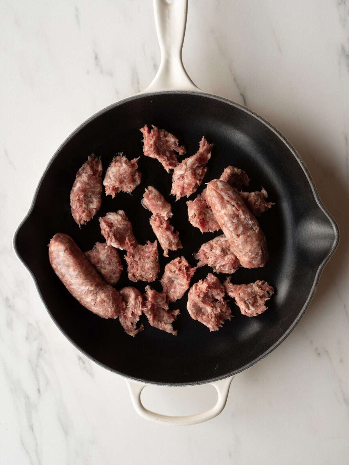 Raw sausage pieces in frying pan