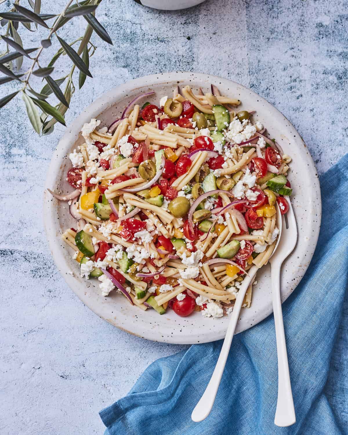 Castelvetrano Greek Pasta Salad on a plate with serving utensils