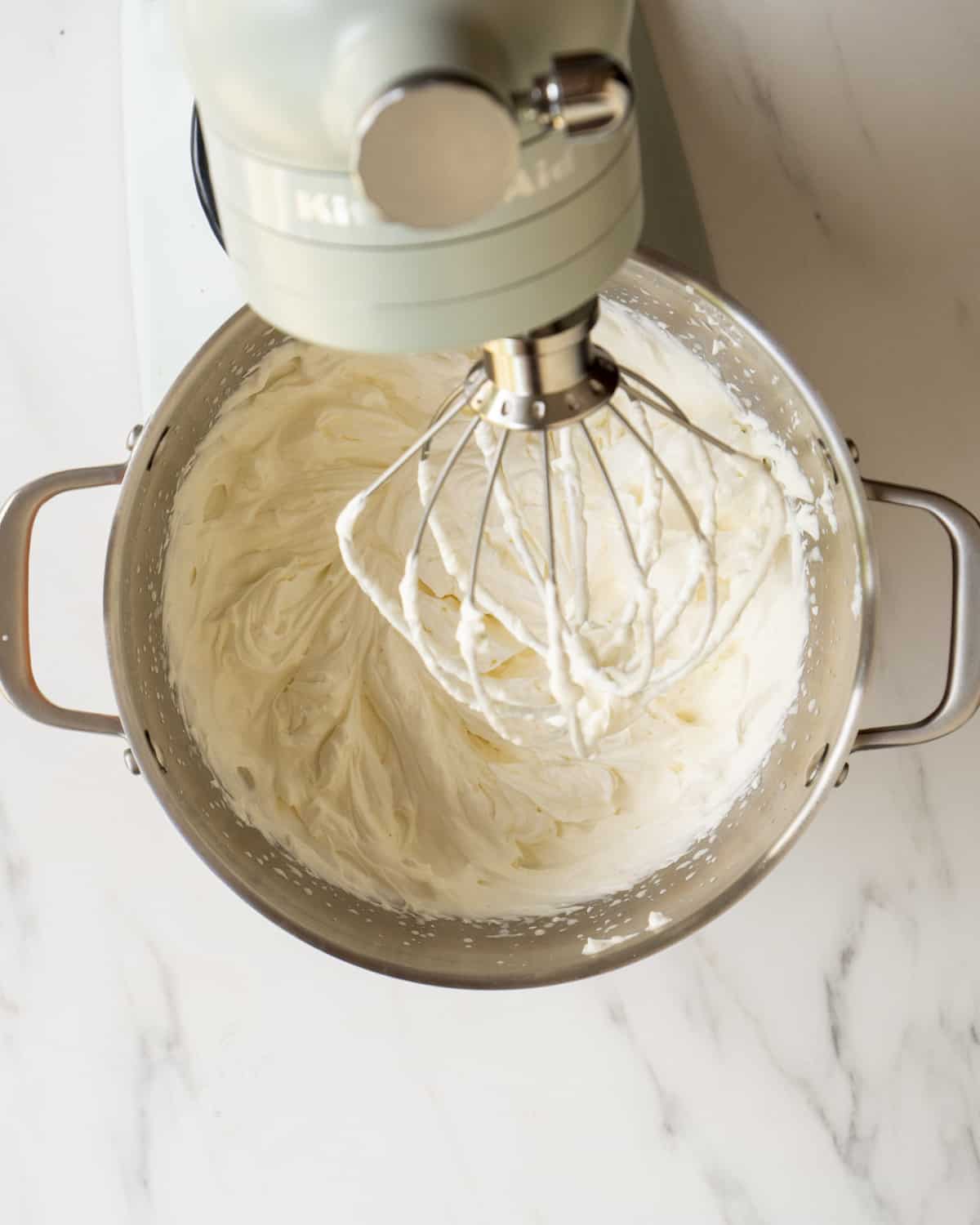 A stand mixer with a bowl full of whipped cream.  