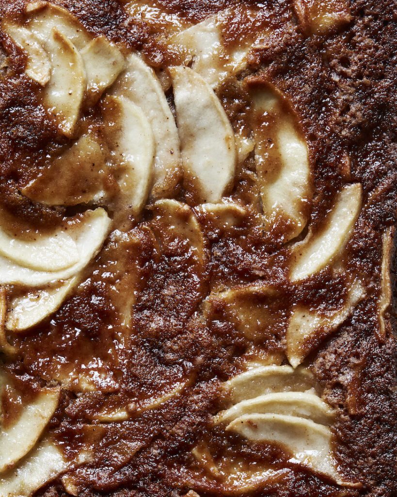 A close-up shot of cinnamon apple cake, with apple wedges peeking out of the cake.