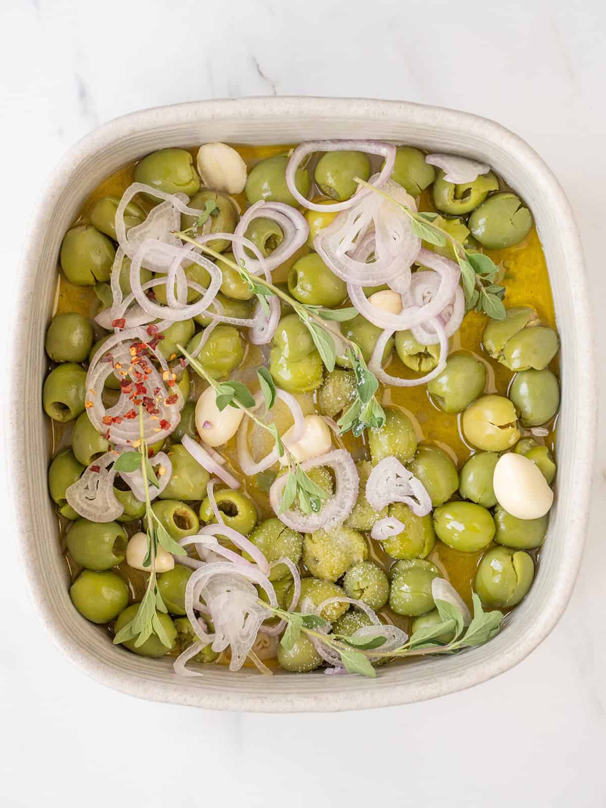 Castelvetrano olives with garlic, shallot, oregano, and olive oil before roasting