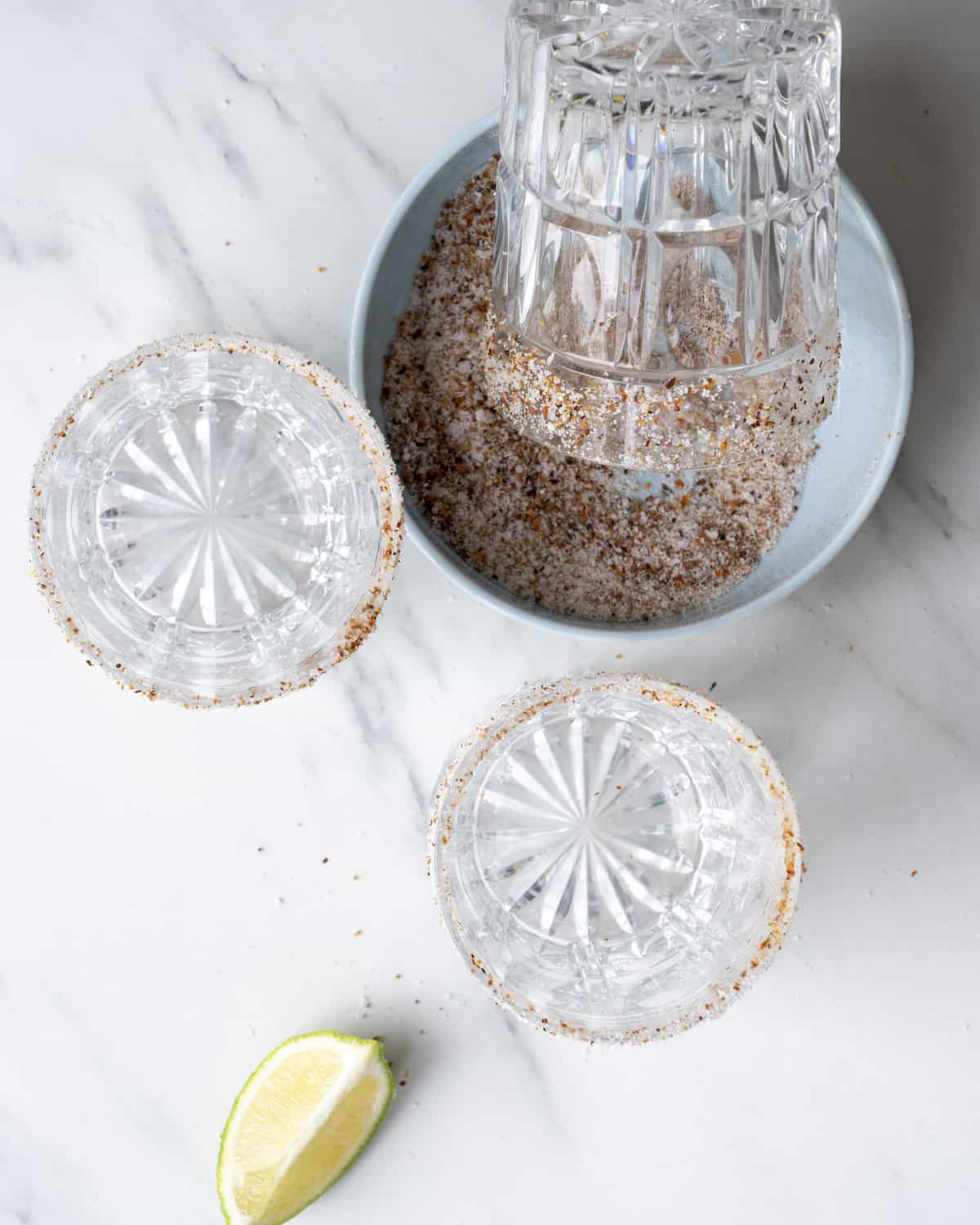 3 cocktail glasses that have had a lime wedge run across the rim and then twisted in a mixture of salt and tajin.