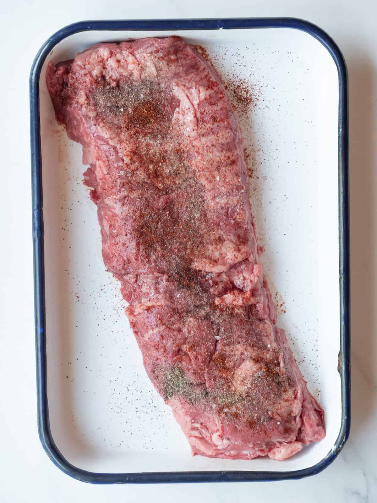 A rectangular platter with skirt steak sprinkled with salt, pepper and chipotle powder.