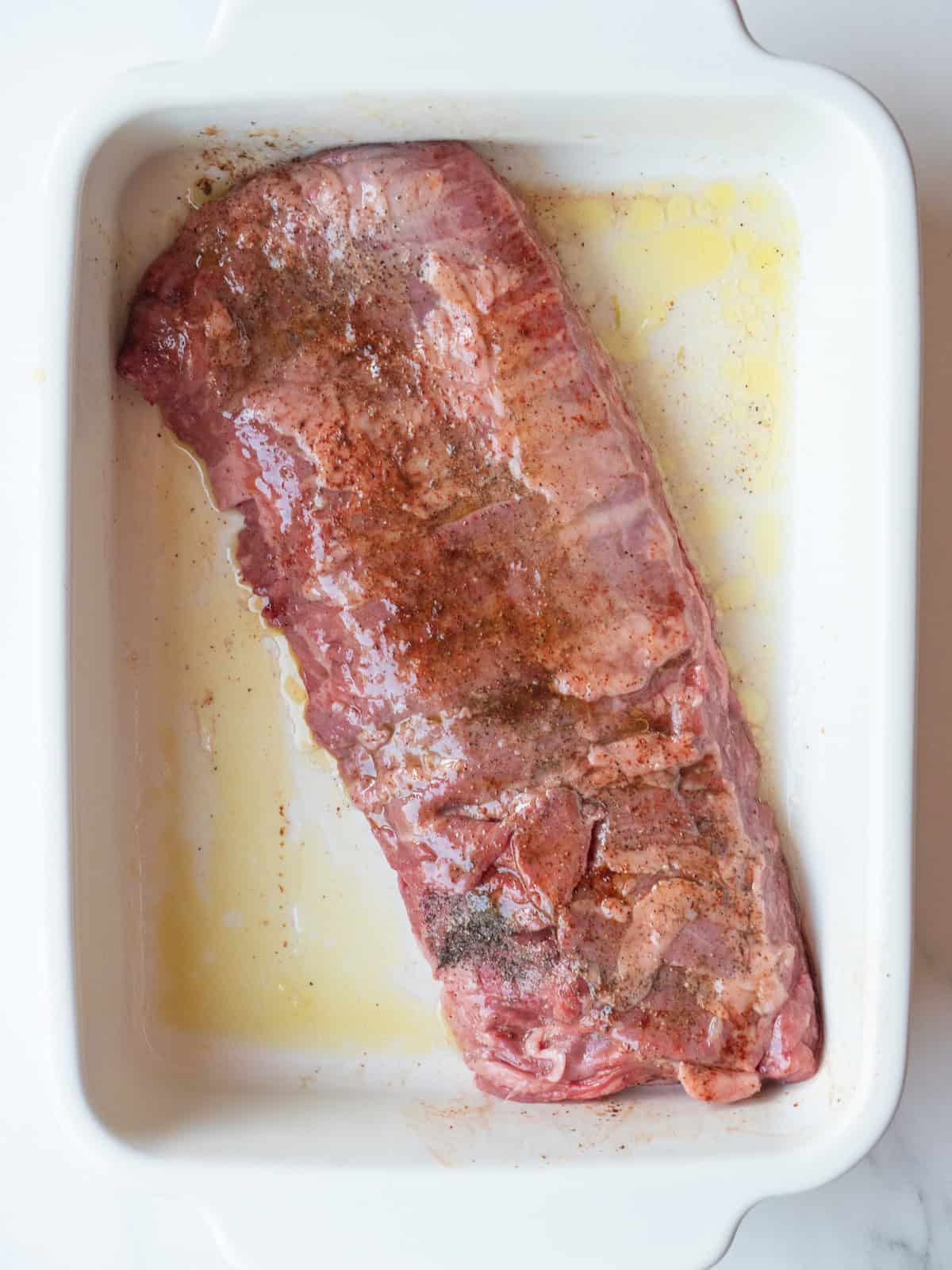 A rectangular platter with olive oil and lemon juice whisked and the skirt steak added to coat and marinate.