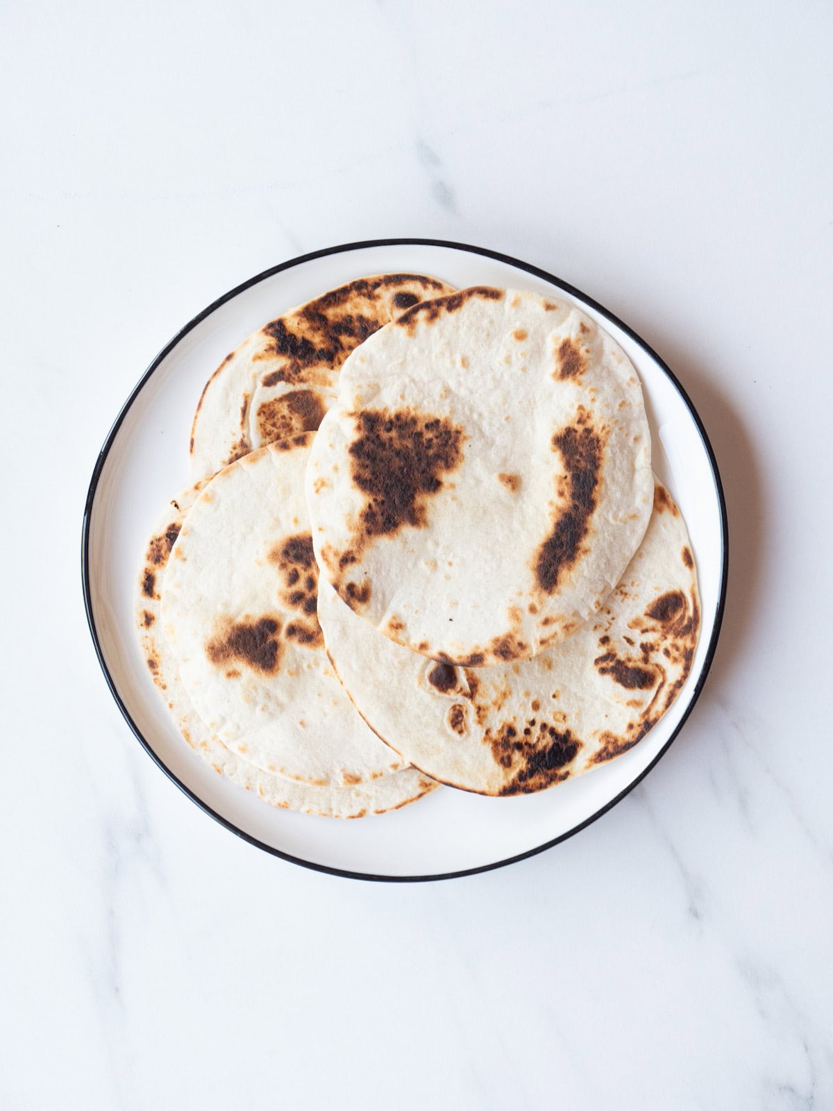 A plate with charred tortillas on it.