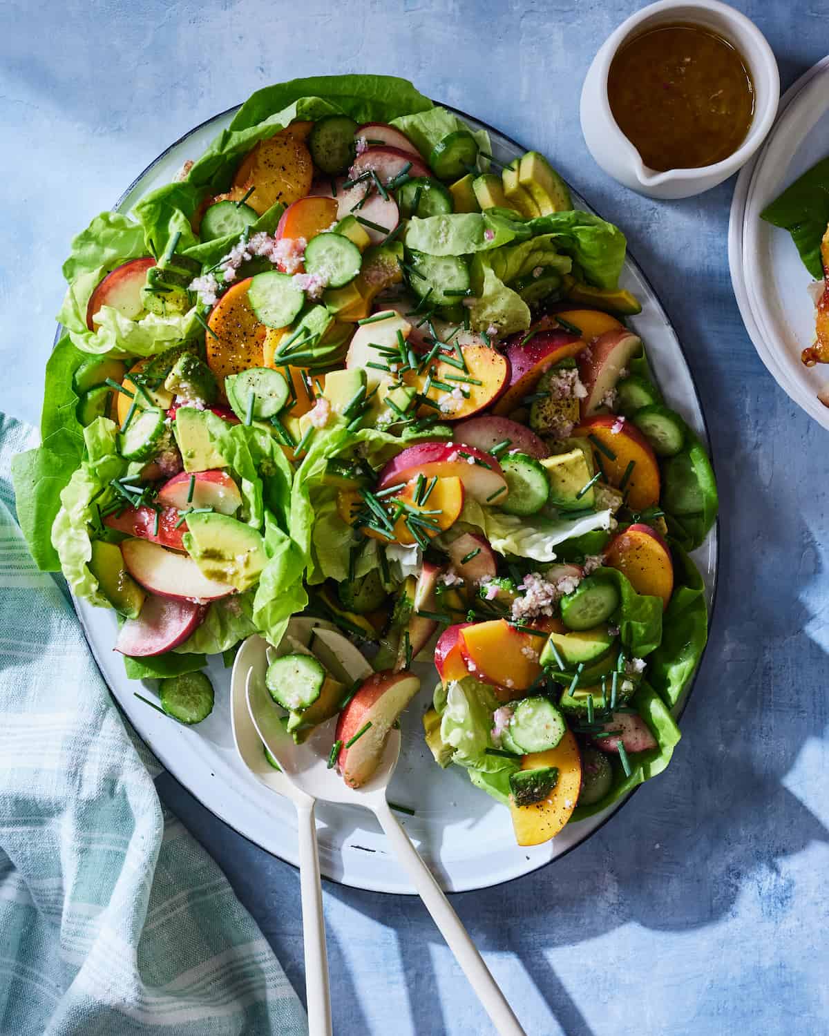 An Avocado Peach Salad on a platter with a lemon parmesan vinaigrette