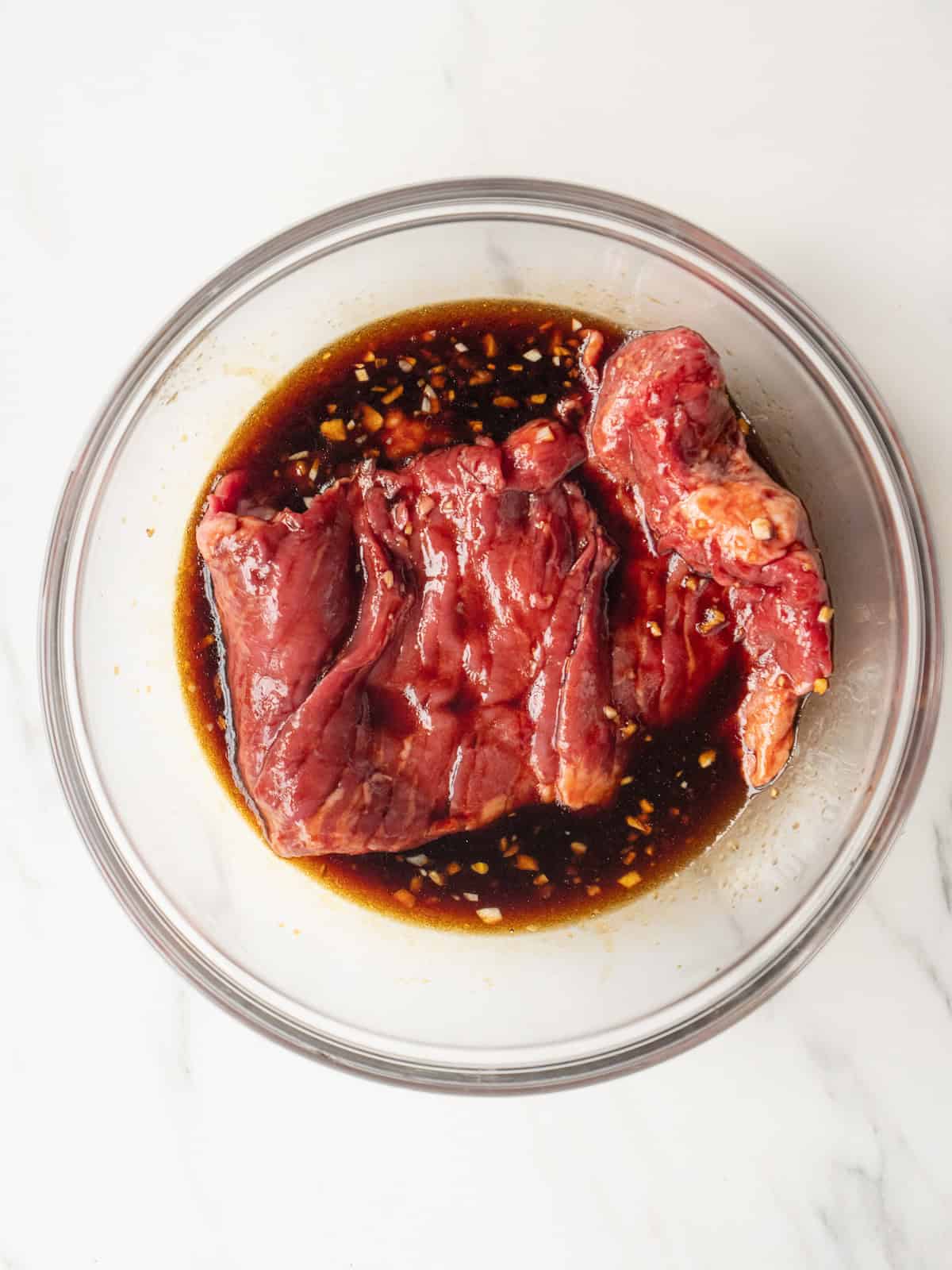 Mixing bowl with steak soaked in the marinade.