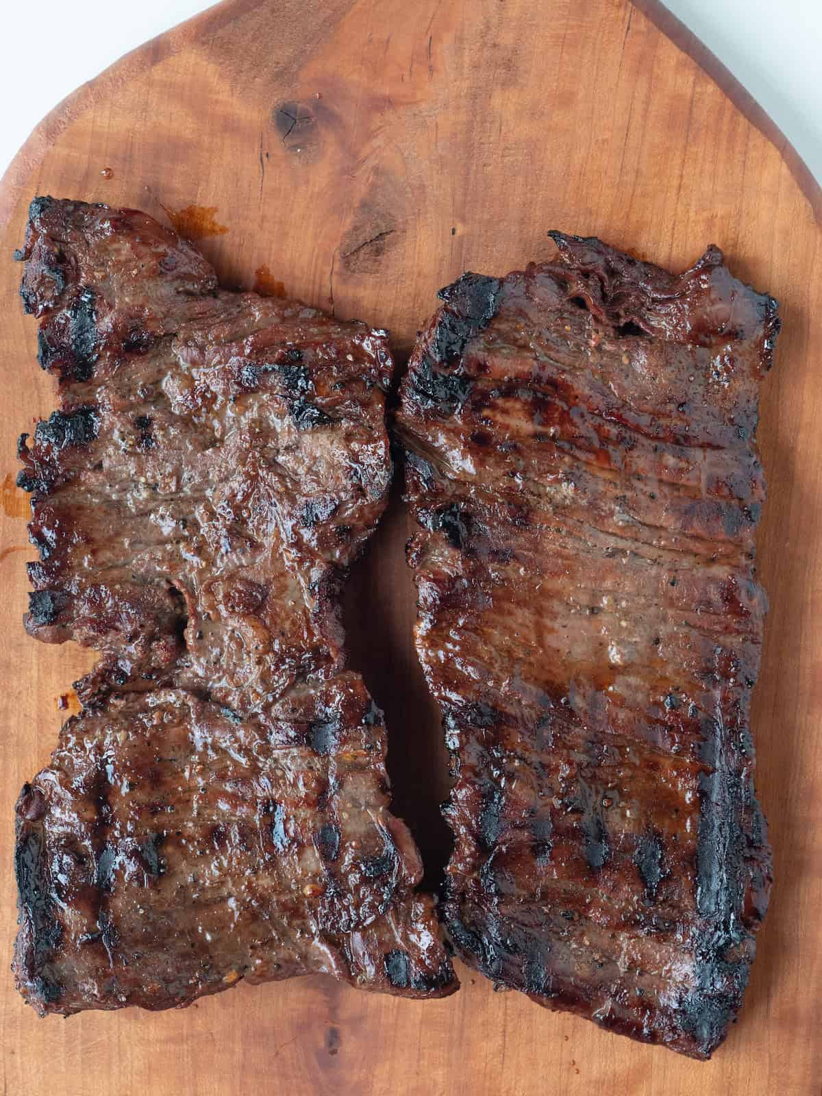 A cutting board with a grilled skirt steak.