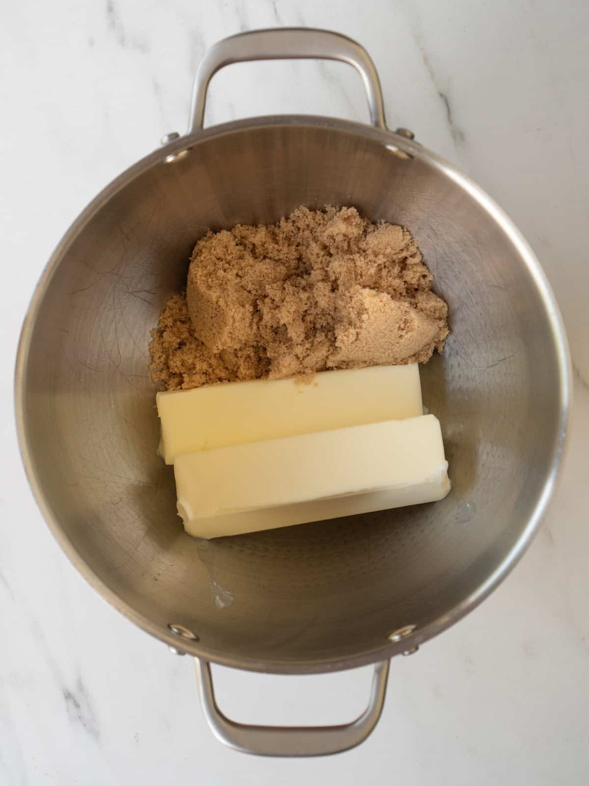 A stand mixer bowl with brown sugar and butter ready to be mixed together.