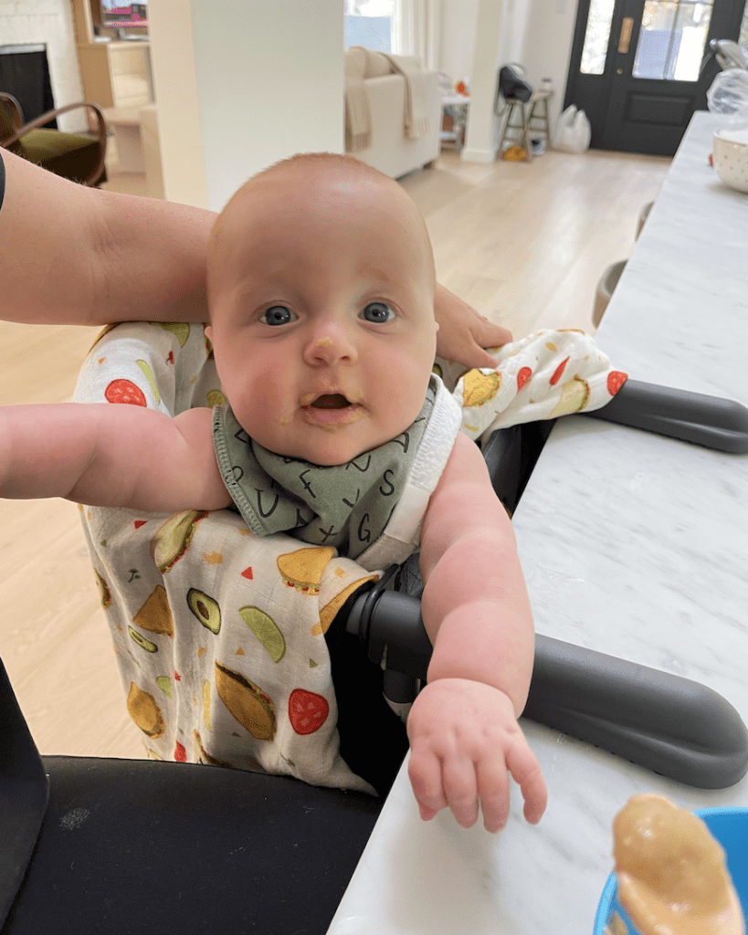 Baby in high chair after with baby food on face
