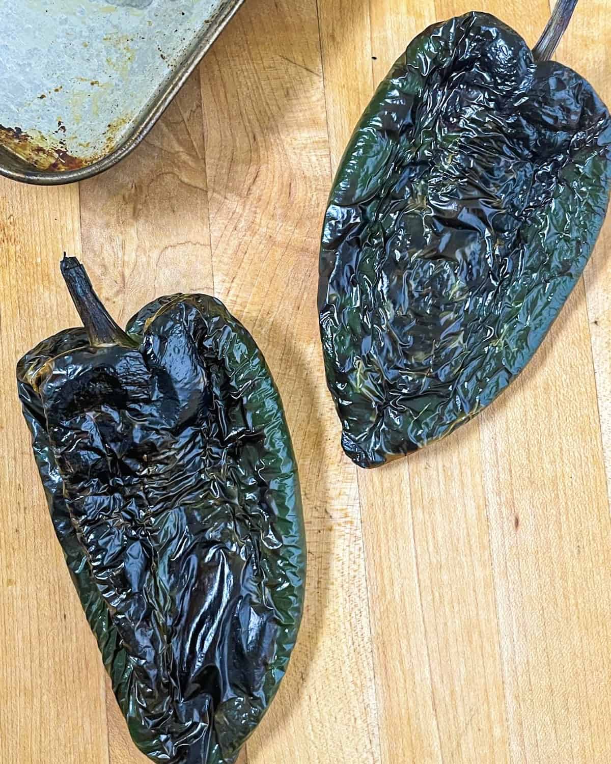 two poblano peppers that have been broiled until blackened on all sides