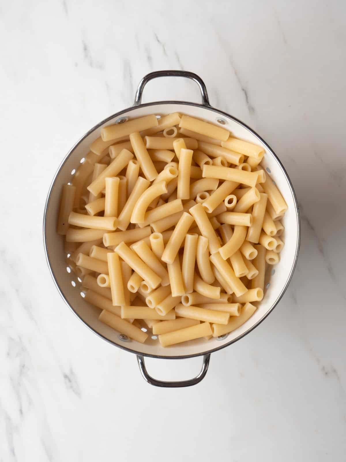 A colander with boiled pasta drained in it.