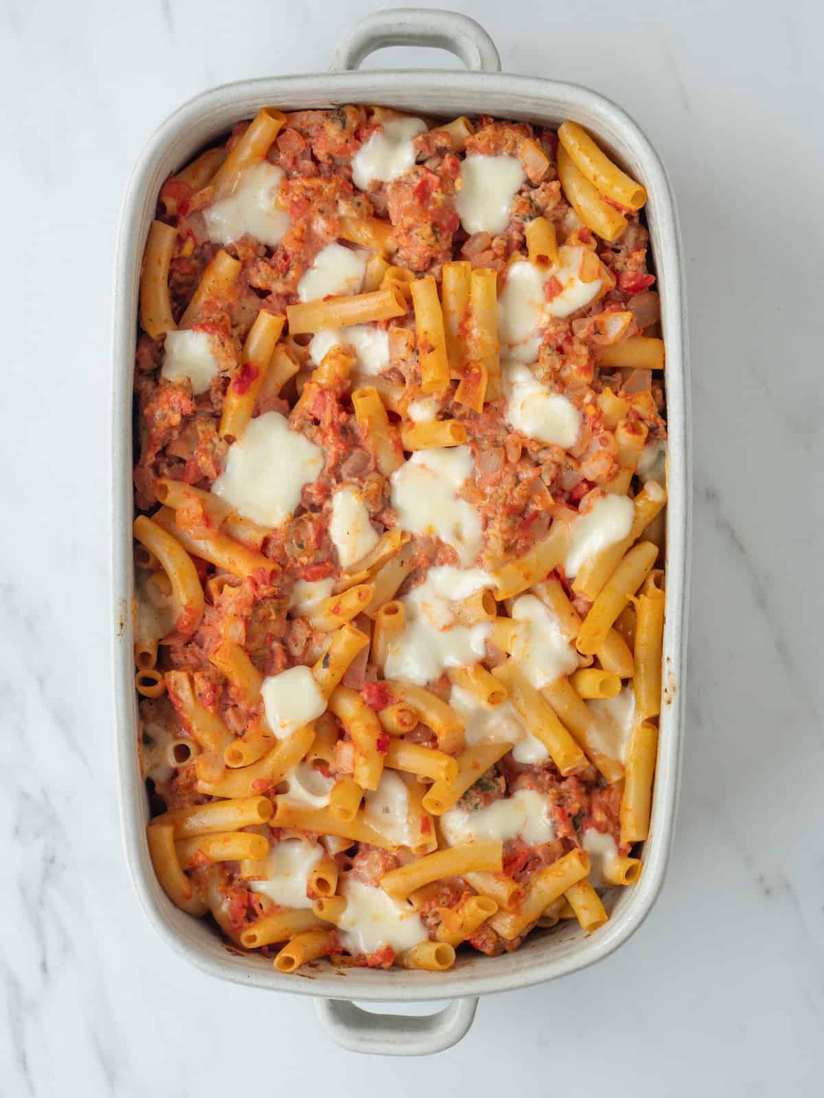 A casserole dish with cheesy chicken sausage pasta bake fresh out of the oven.