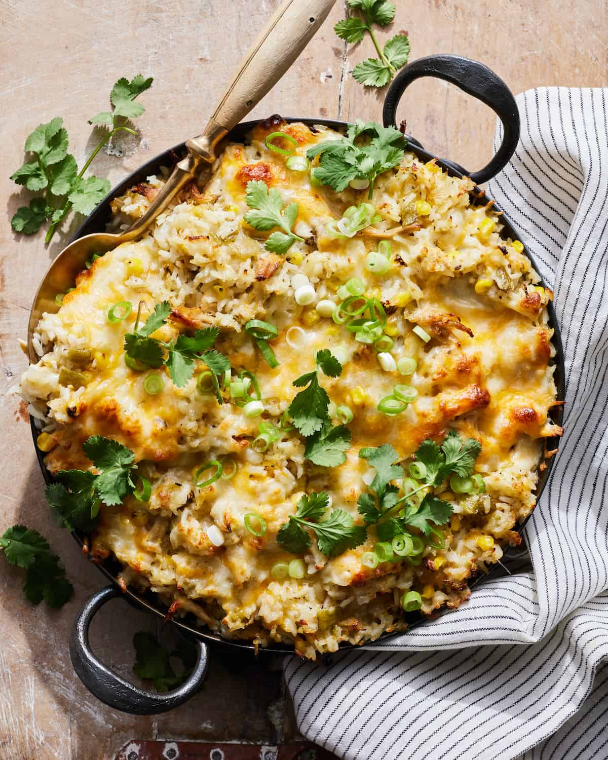 Chicken Rice and Cheese Casserole is served in a black round metal braiser. The casserole is garnished with lots of cilantro and scallions.