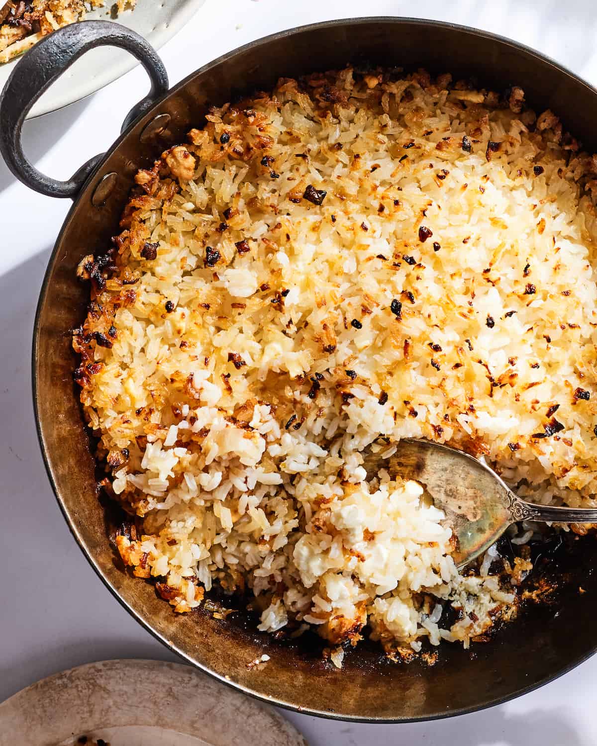 Crispy Rice from in a skillet with an aged spoon scoping up some rice.  