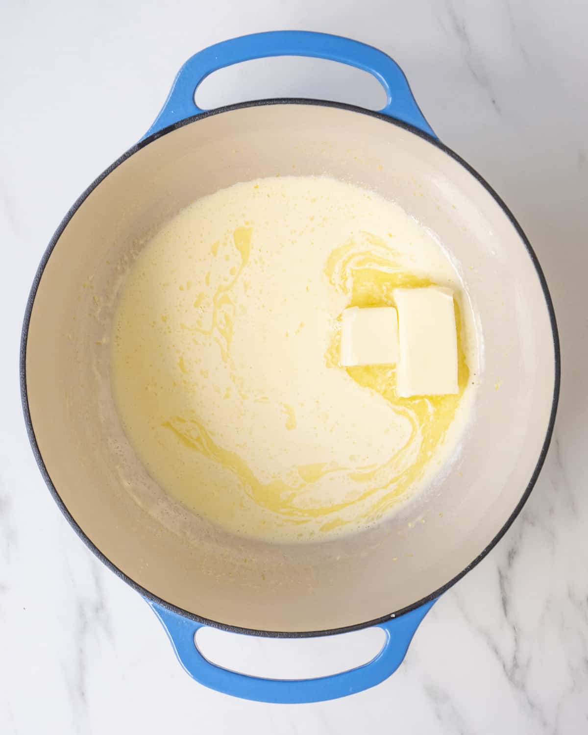 A large blue skillet with lemon zest and cream and butter.  