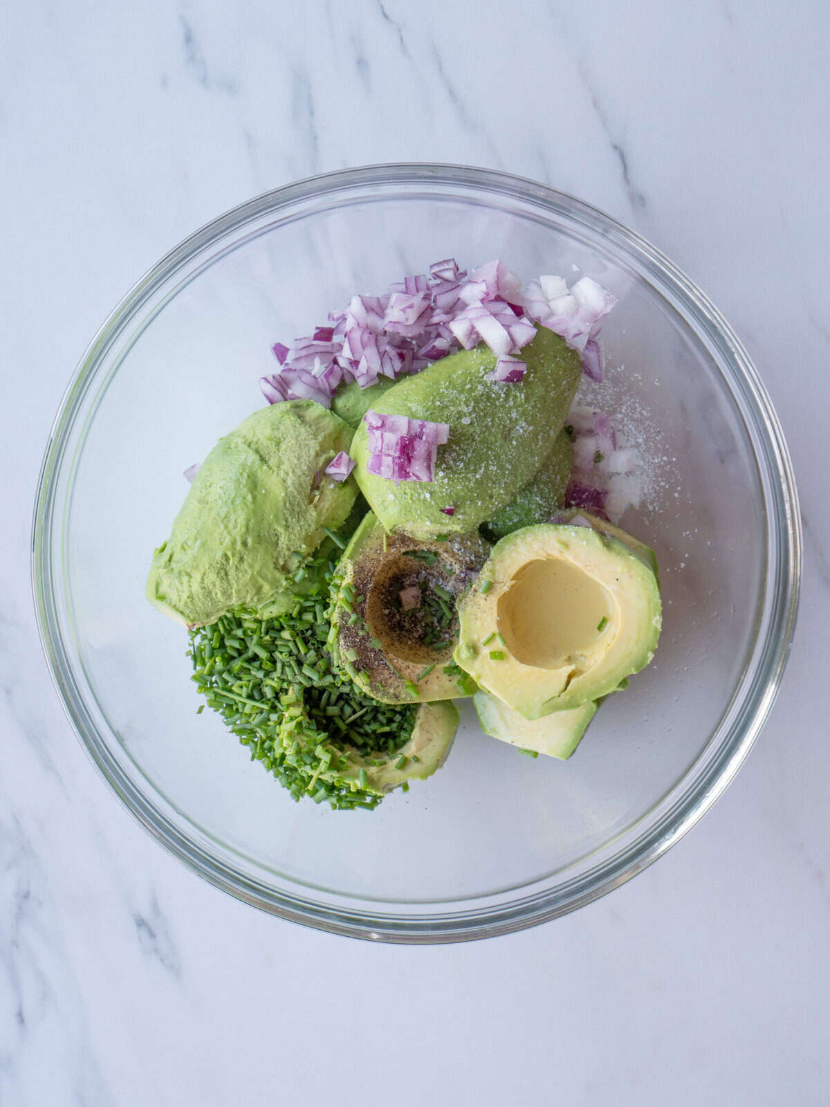 Avocado, onion, and herbs in bowl