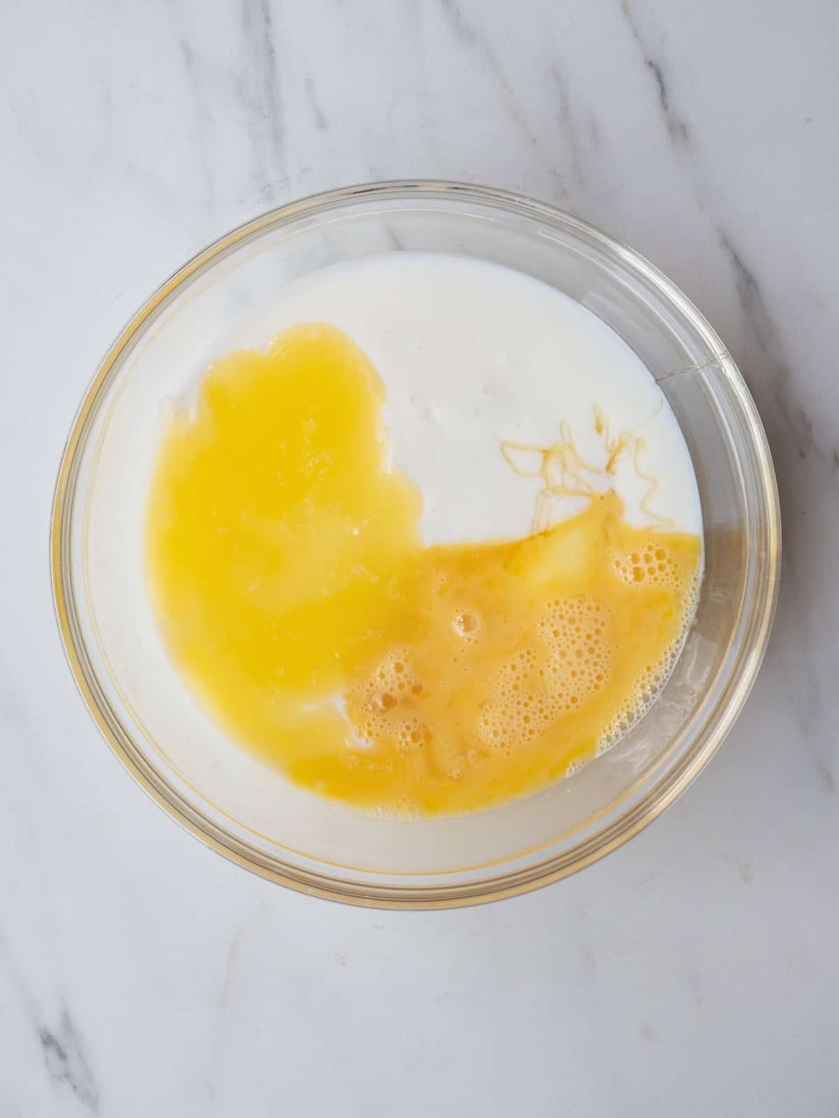 A mixing bowl with butter, buttermilk, eggs and agave added to make buttermilk pancakes batter.