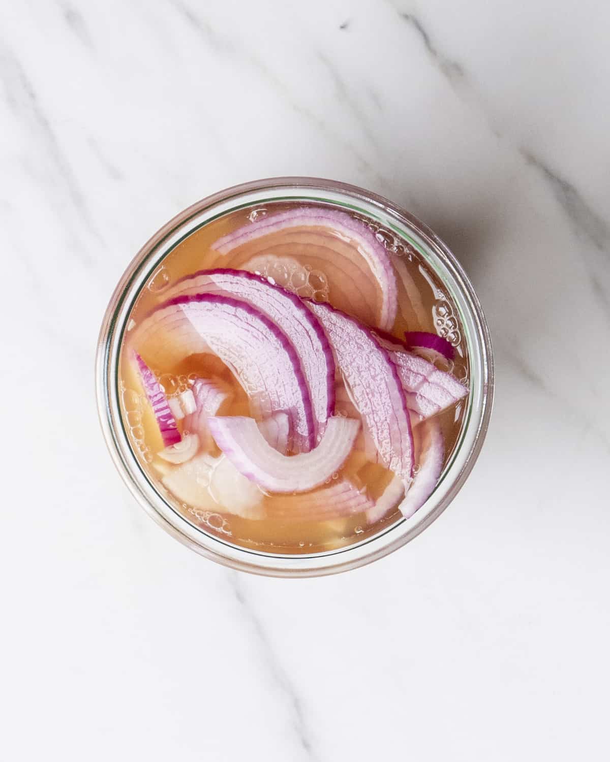 A small bowl with sliced red onions picked in a mixture of apple cider vinegar, sugar, salt and water.