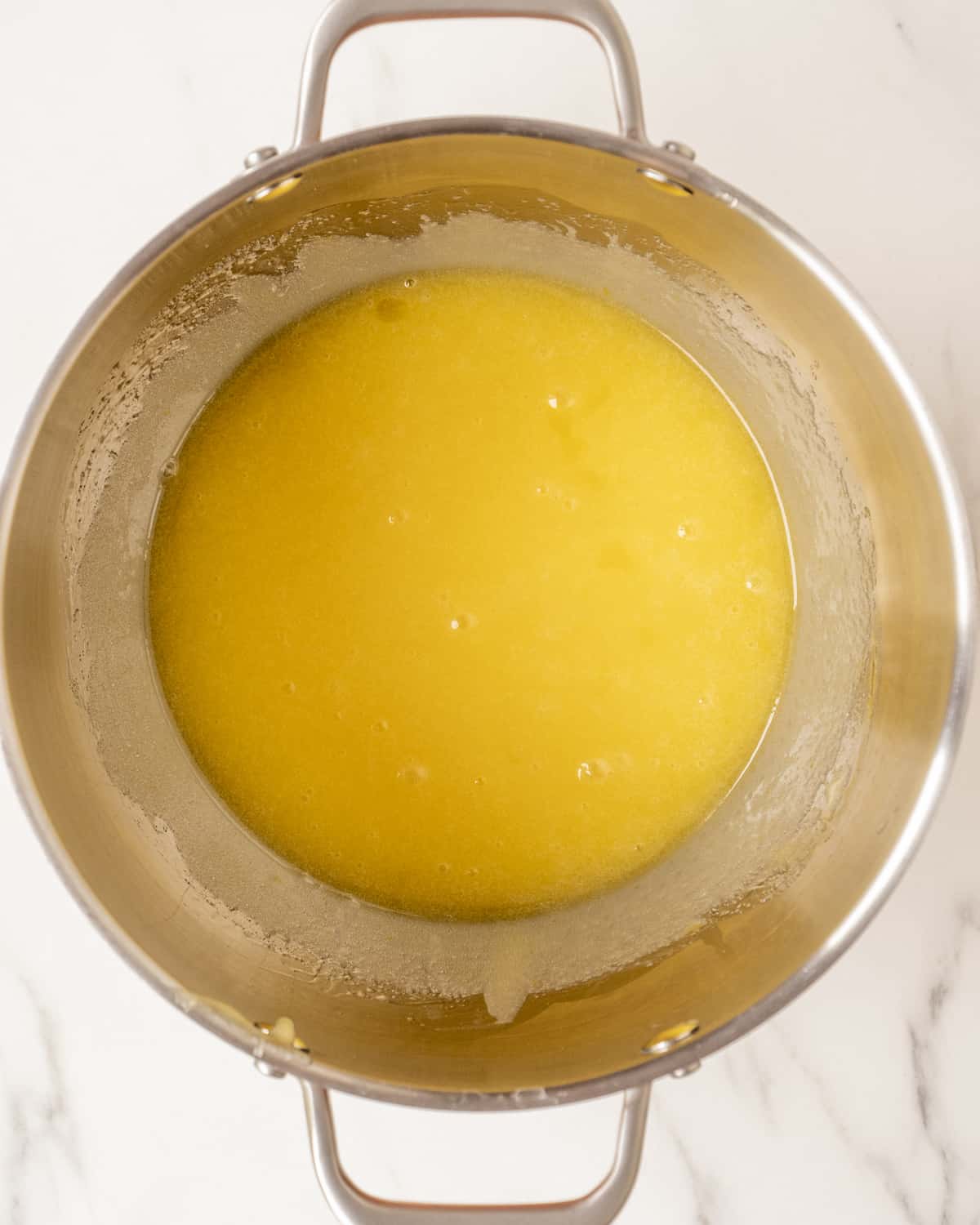 A stand mixer bowl with a mixture of oil, eggs and sugar