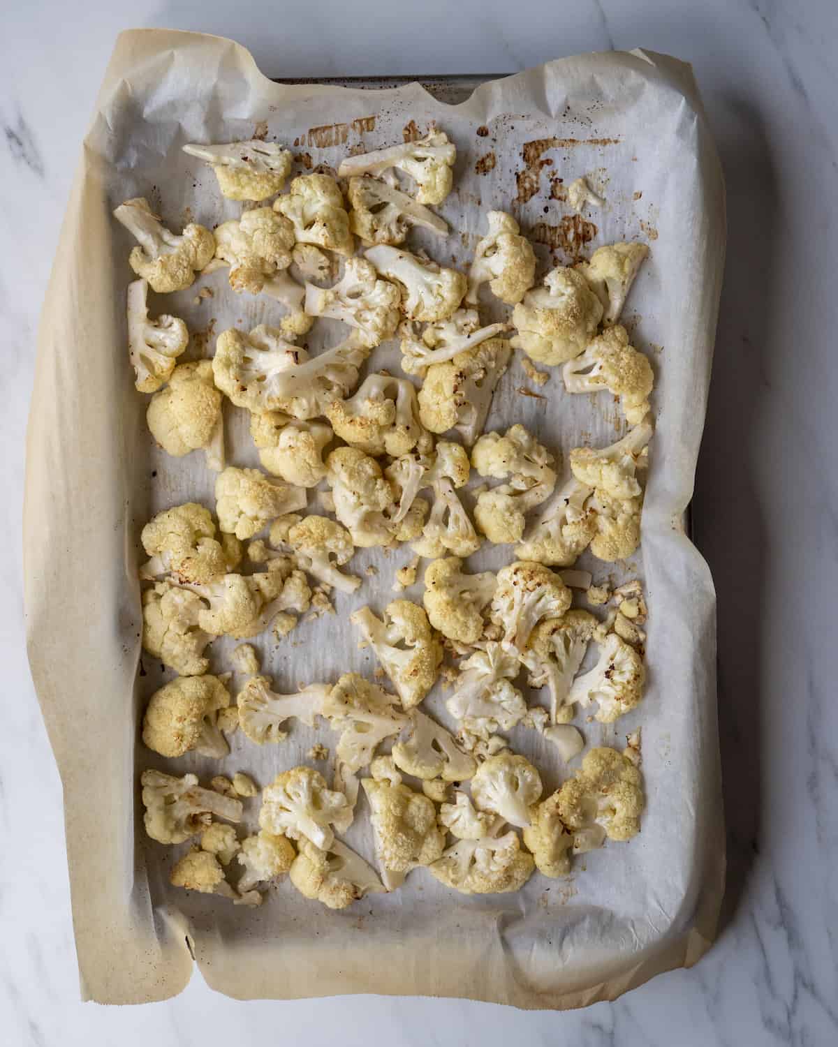 A parchment lined baking sheet with roasted cauliflower florets.