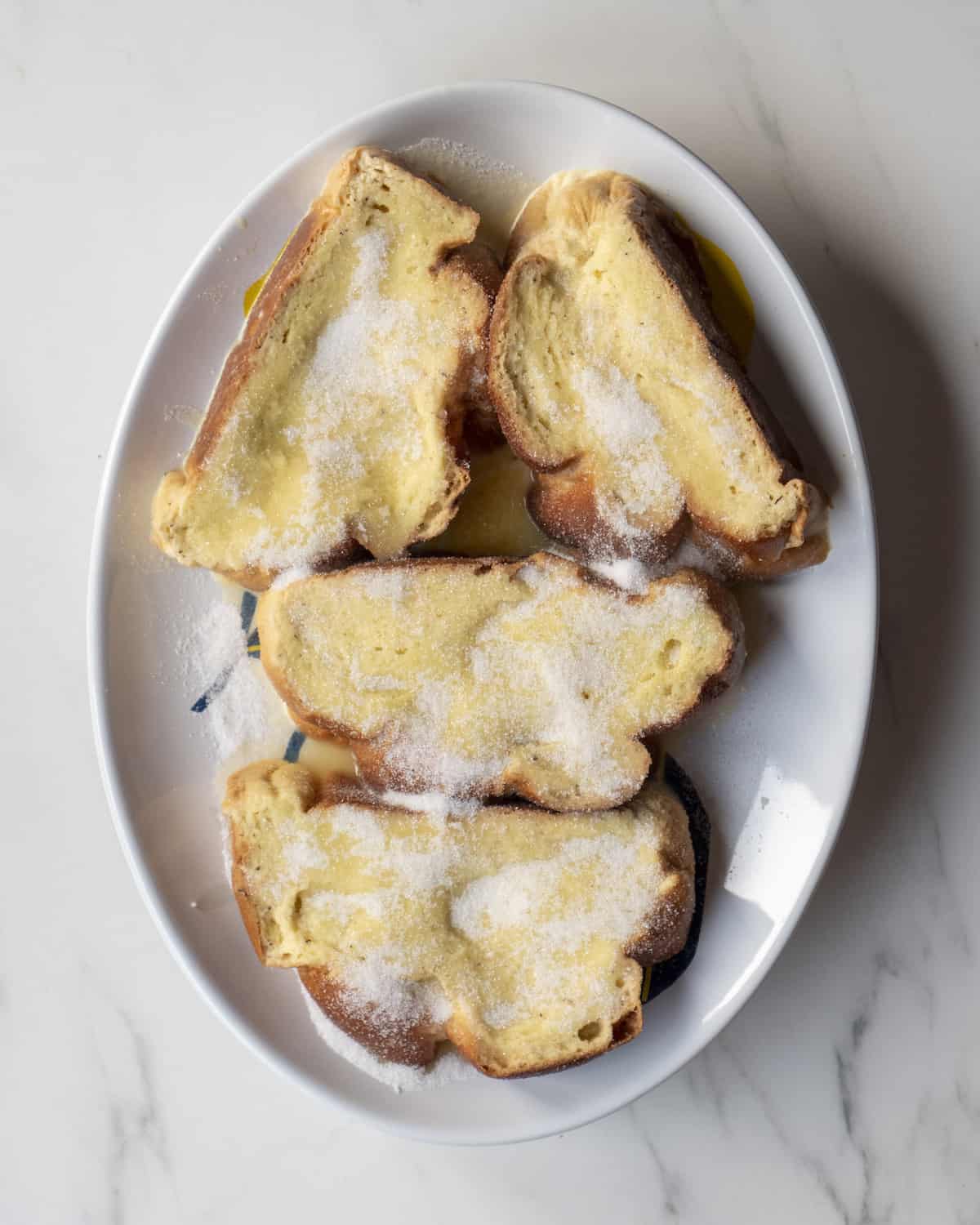 A plate with slices of bread that have been soaked into french toast batter and taken out of the excess batter.