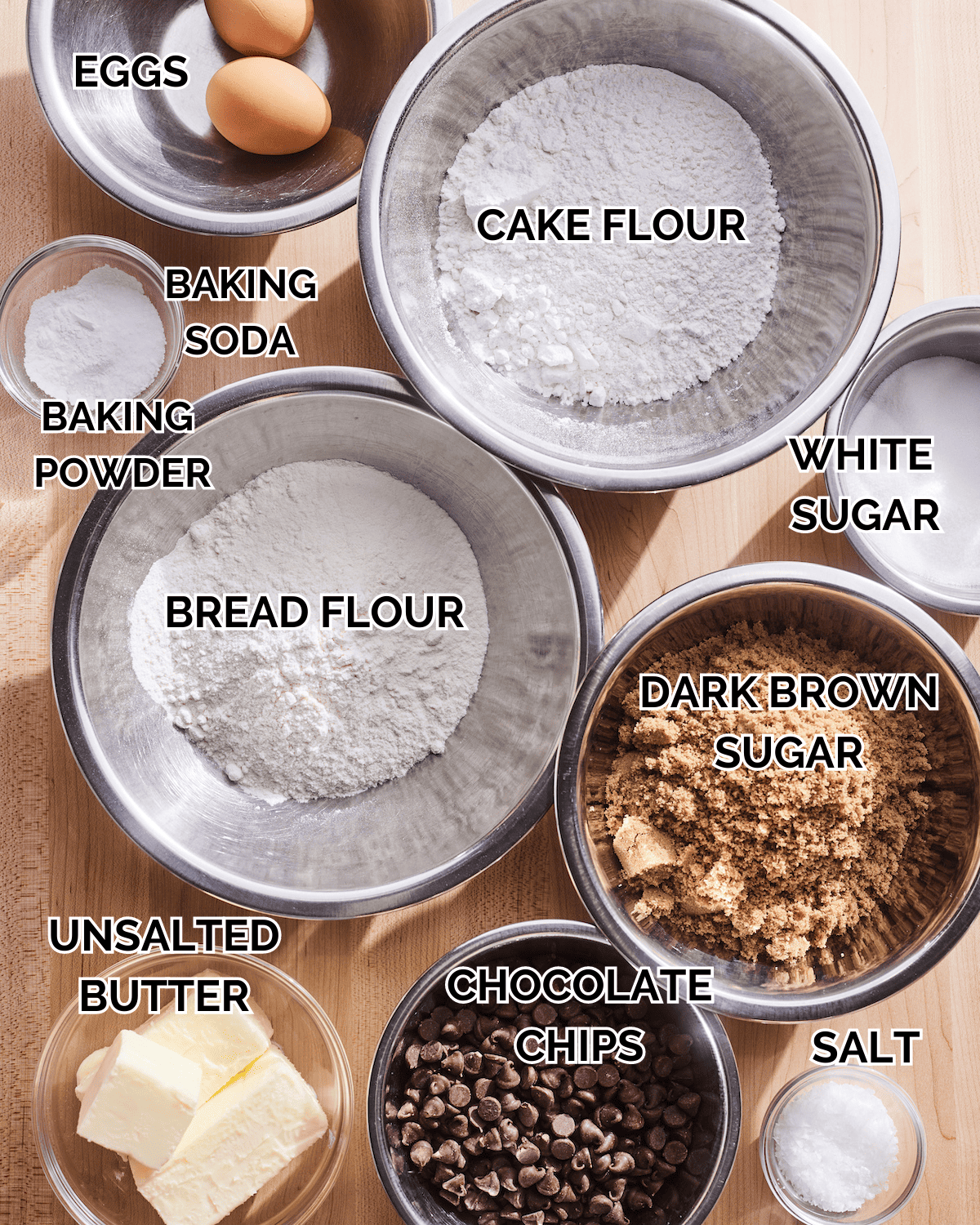 The Best Chocolate Chip Cookie Recipe Ingredients measured out in metal bowls on a wooden background