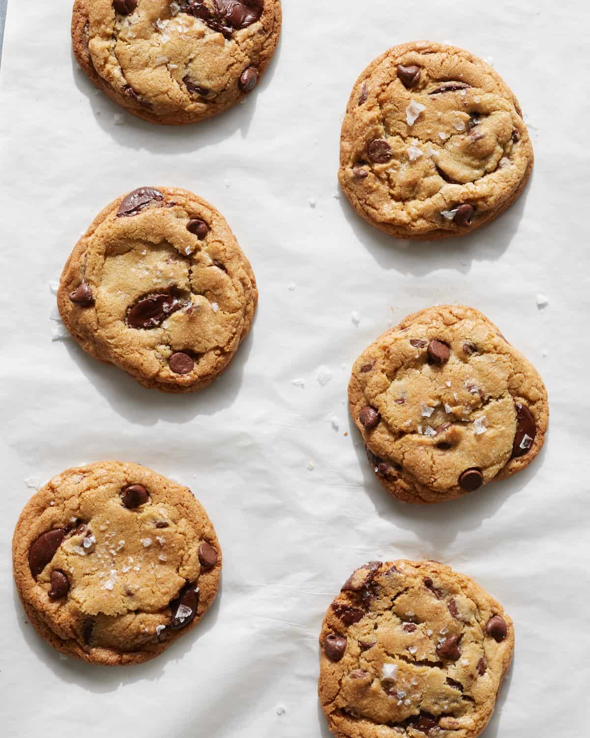 Freshly baked Chocolate Chip Cookies on a baking sheet lined with parchment.