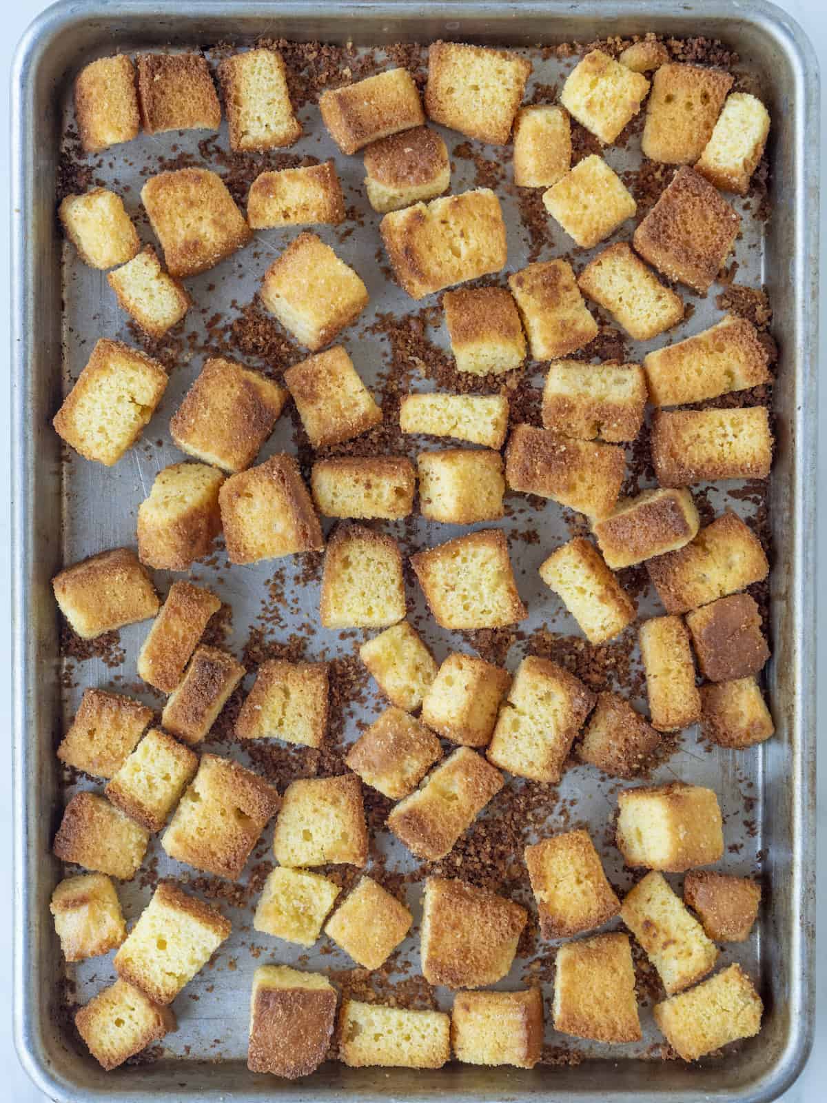 A baking dish with cubed cornbread toasted.