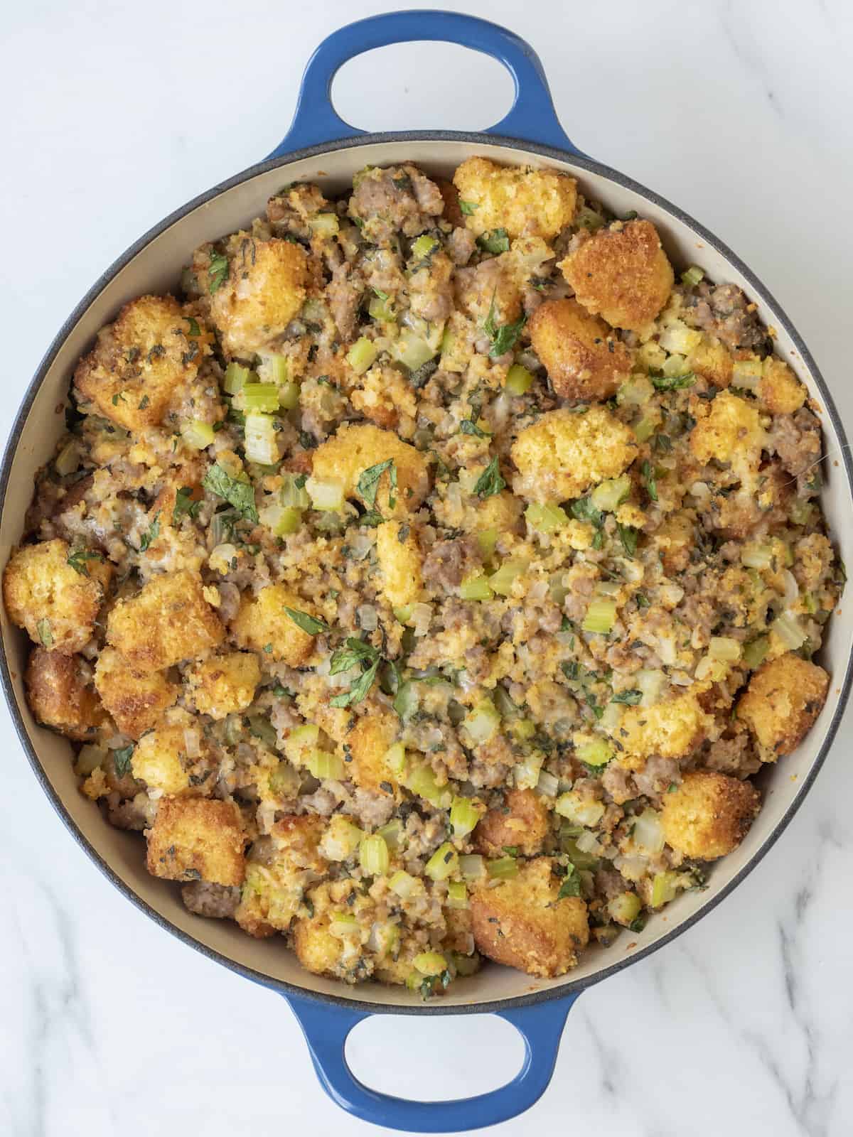A large blue dutch oven with cornbread stuffing.
