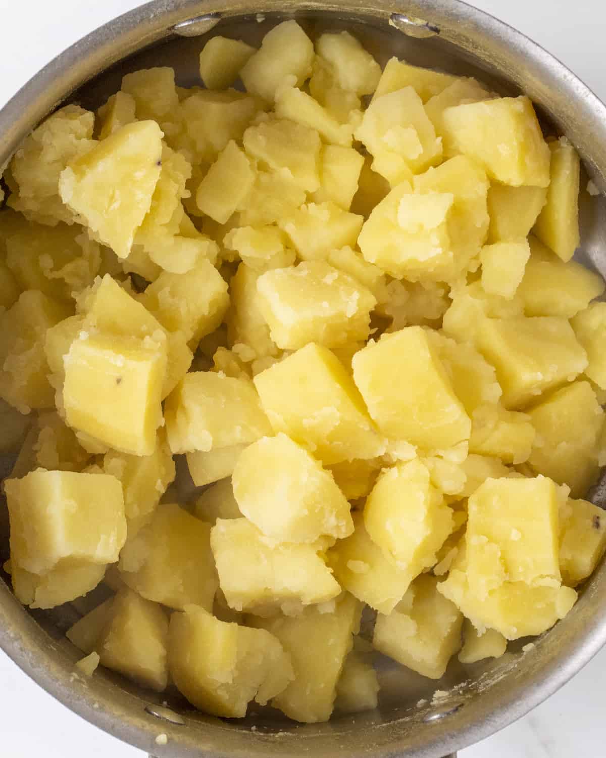 A large pot filled with the cubed potatoes that have been boiled.  