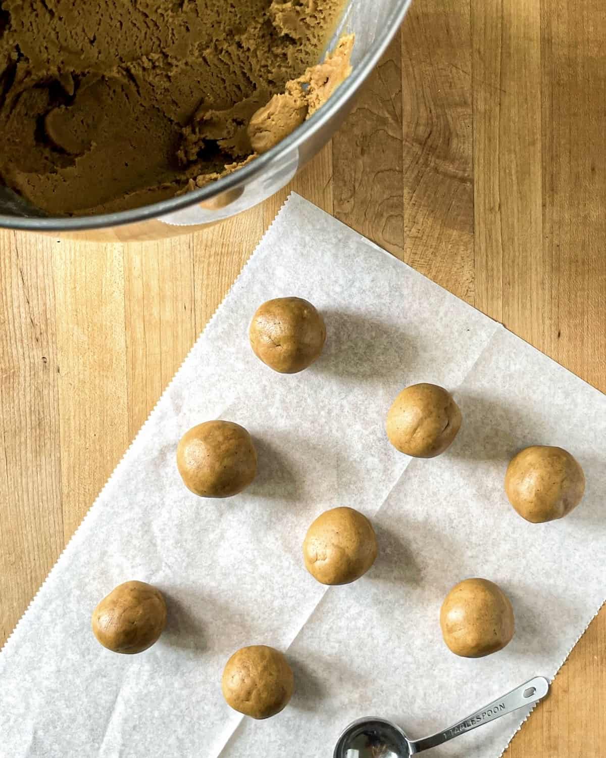 Molasses Cookie dough rolled out in 2 tablespoon sized balls on a piece of parchment paper