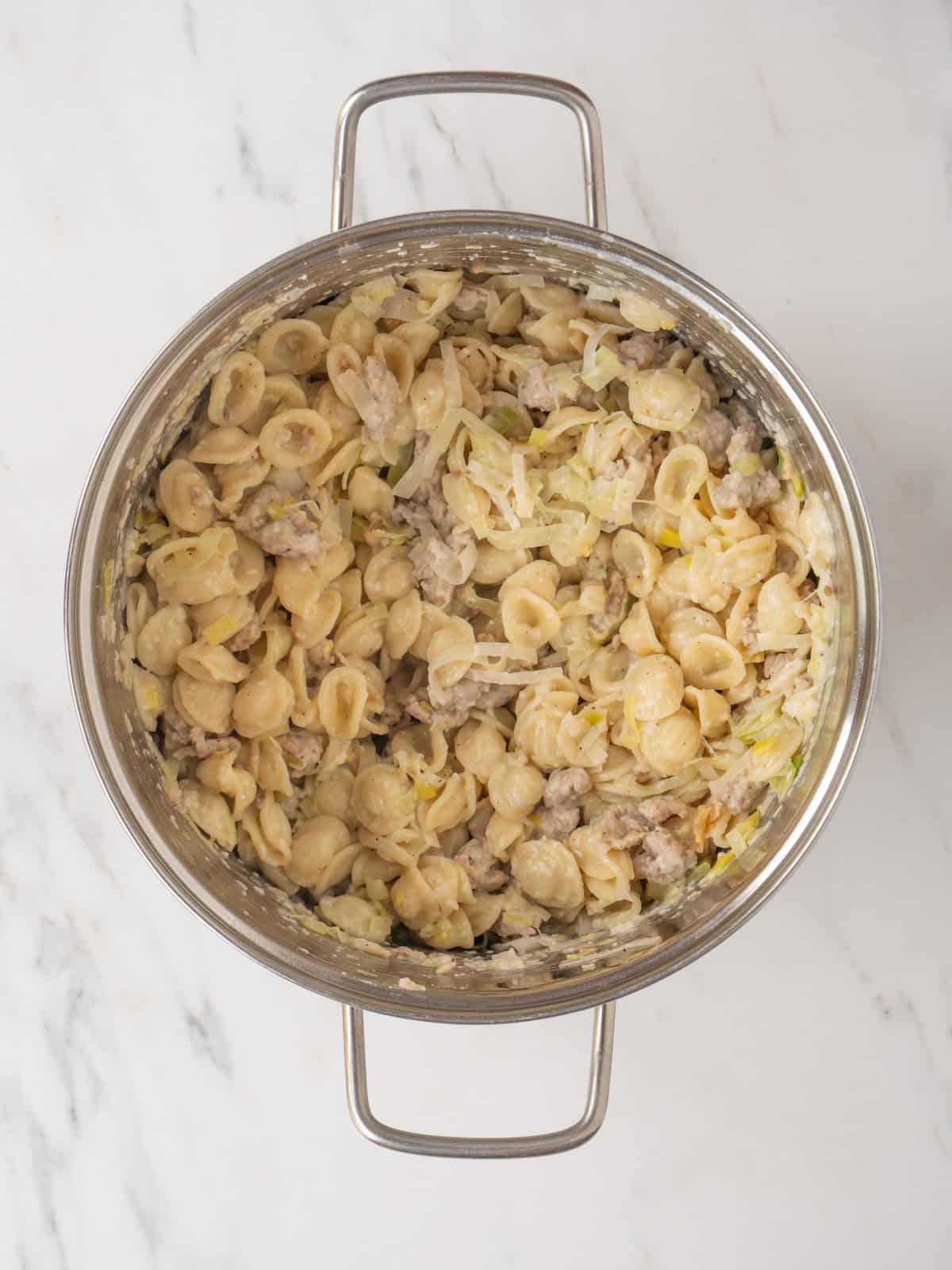 A pot with sausage and leeks orecchiette pasta.