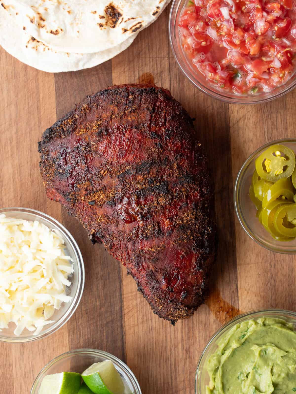 Grilled meat with taco toppings arranged.