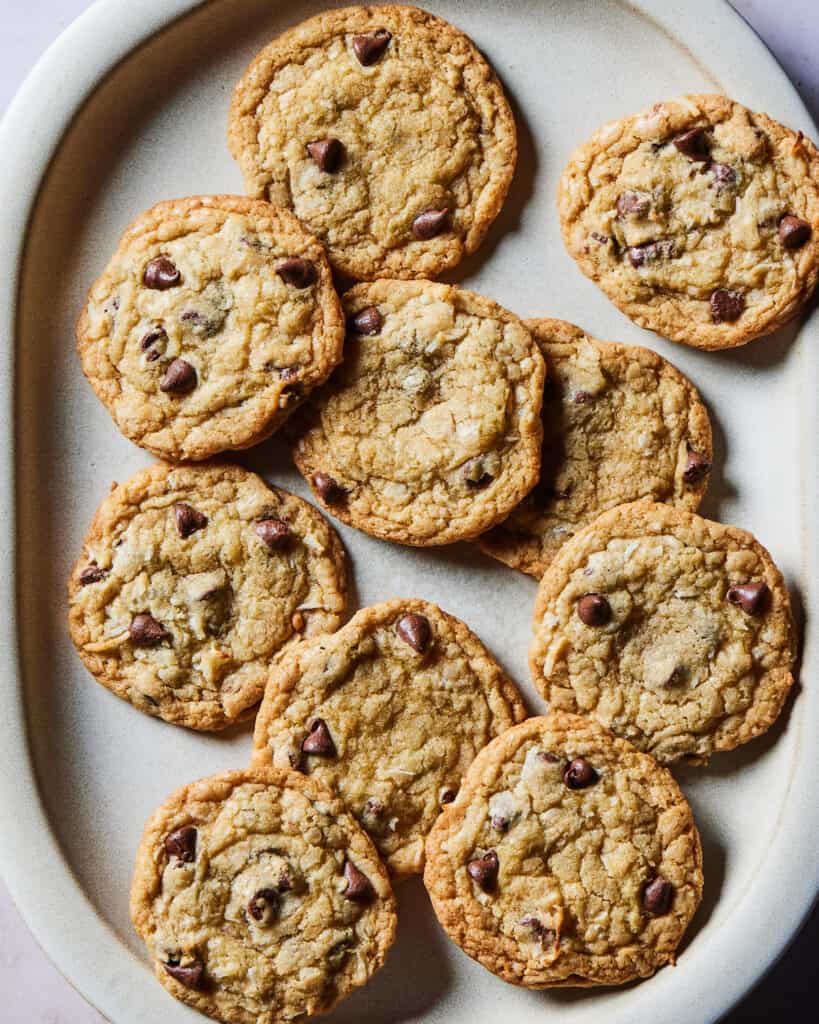 Many coconut chocolate chip cookies stacked over each other on an oval serving platter.