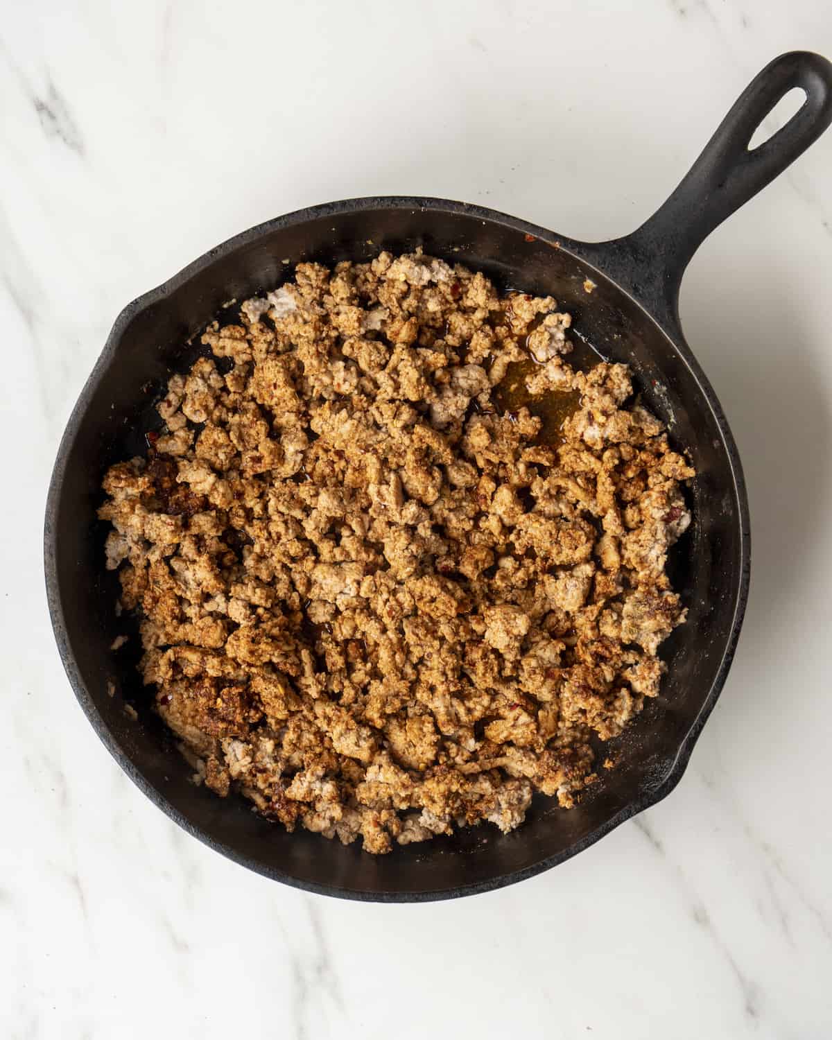 A skillet with sautéed and seasoned ground chicken