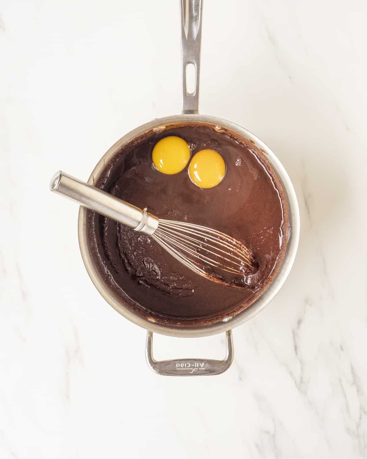 A pot filled with brownie batter and 2 eggs.  